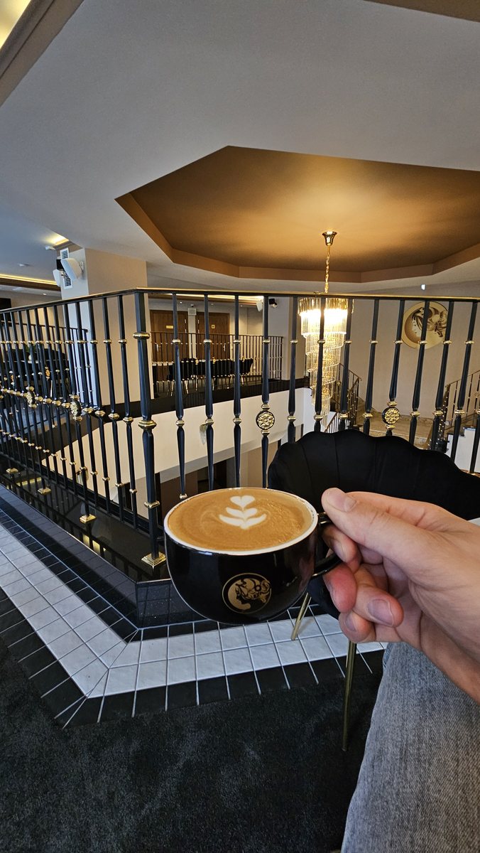 Cappuccino z latte art w czarnej filiżance w Hotelu Juvena