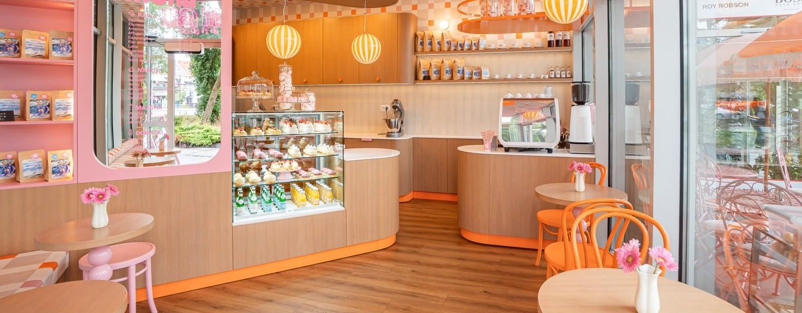 Ma Ma Cafe w Świnoujściu: zaokrąglony bar, witryna z deserami i biały ekspres Nuova Simonelli Appia Life Compact