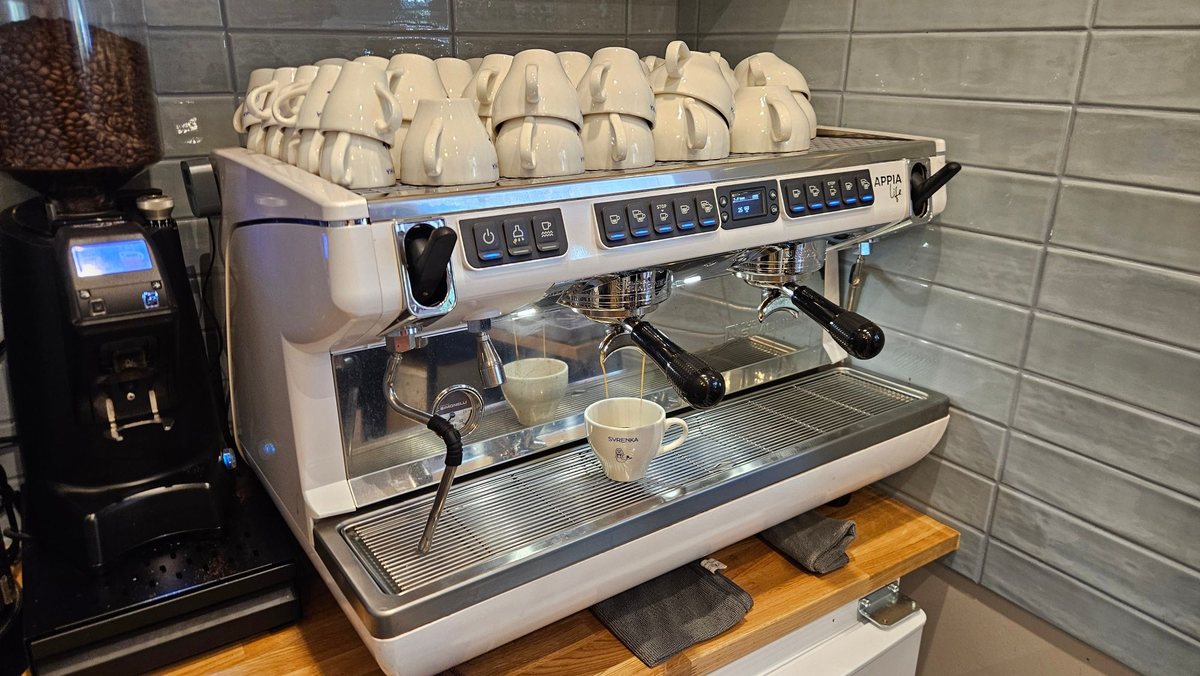 Biała Nuova Simonelli Appia Life XT z młynkiem i filiżankami na podgrzewaczu w restauracji Syrenka